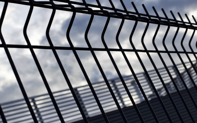 Close up of fences of a prison and cloudy sky on background